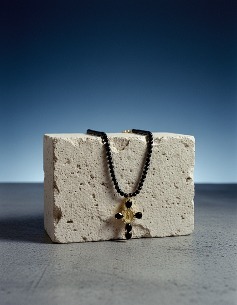 Black beaded necklace with a yellow pendant on a textured block against a blue gradient background
