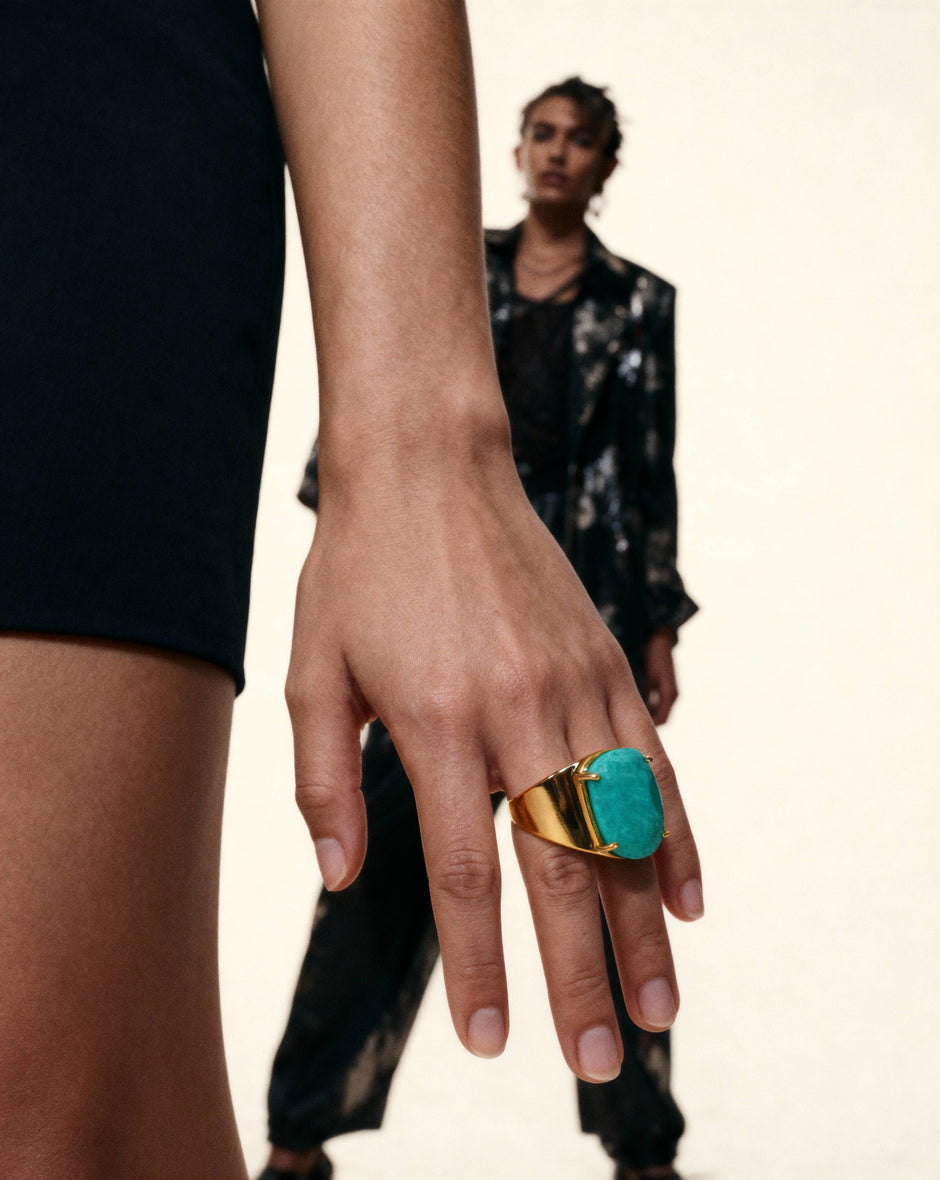 Hand wearing a turquoise ring with a blurred person in the background