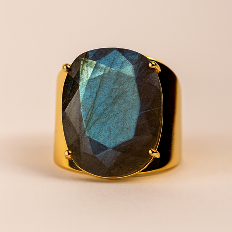 Gold ring with a labradorite stone on a beige background
