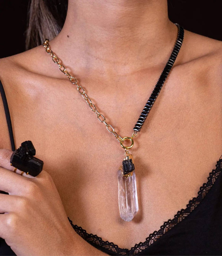 Necklace with a crystal pendant worn by a person, against a black background