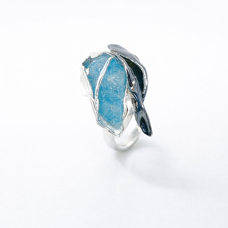 Silver ring with a large blue stone on a white background