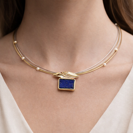 Necklace with a blue pendant on a person wearing a white top
