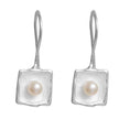 Pair of silver earrings with pearl centers on a white background