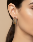 Close-up of a woman wearing a silver hoop earring with a beige background