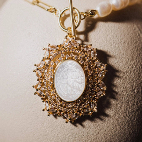 Gold pendant with a central coin on a textured beige background