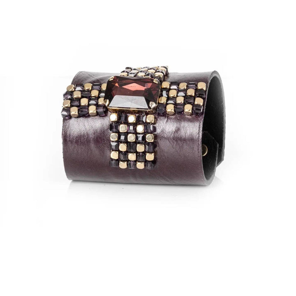 Angled close-up of garnet-toned crystal and hand-applied beadwork on leather cuff