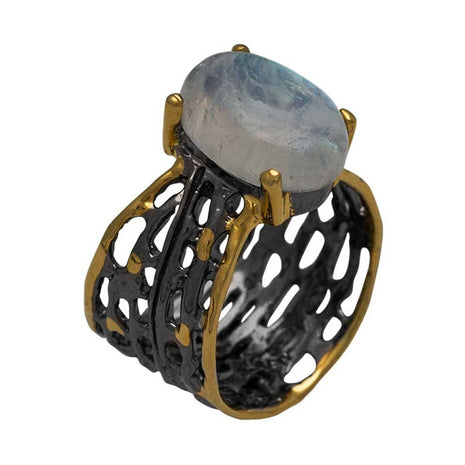 Ring with gold and black design and central stone on a white background