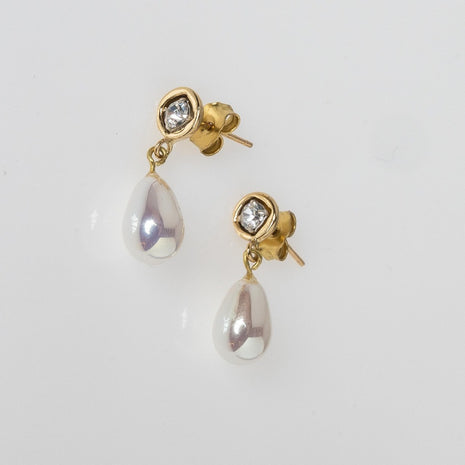 Gold earrings with teardrop-shaped pearls on a light gray background